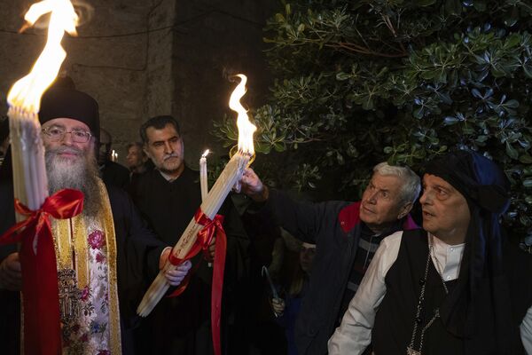 Greek Orthodox faithful light their car Niles with the Holy Fire, transferred from the Holy Sepulchre in Jerusalem, at a church in Athens. - Sputnik International
