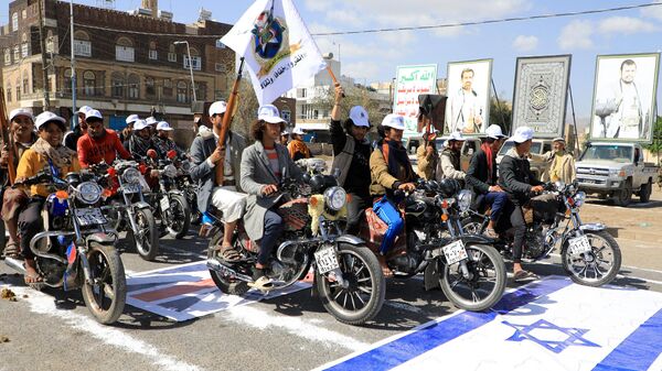 Yemeni men riding motorcycles drive over an Israeli flag painted on the asphalt in the Houthi-run capital Sanaa, during a march in support of the Palestinians amid ongoing battles between Israel and Hamas militants in the Gaza Strip, on February 29, 2024. - Sputnik International