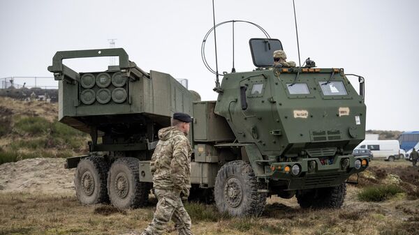 A soldier walks in front of a M142 HIMARS High Mobility Artillery Rocket System during the Dynamic Front military exercise led by the United States at the Oksboel Training and Shooting Range in Oksbol, Denmark on March 30, 2023. - Sputnik International