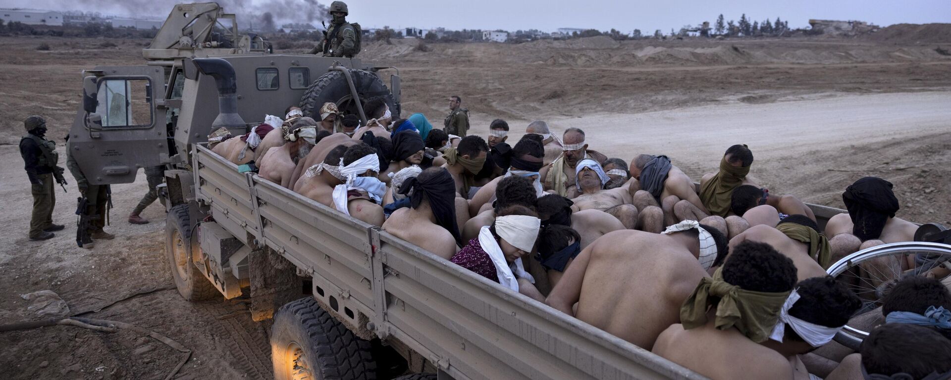Israeli soldiers stand by a truck packed with bound and blindfolded Palestinian detainees, in Gaza, Friday, Dec. 8, 2023. - Sputnik International, 1920, 18.06.2024