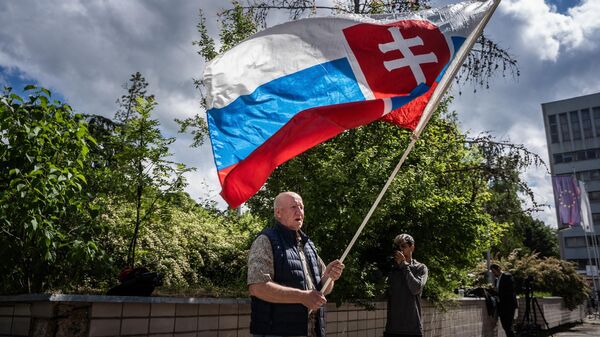 Picture taken on May 16, 2024 shows a man named Vladimir Petko holding a Slovakia flag, who came to pray in front of the hospital in Banska Bystrica, Slovakia where Slovak Prime Minister Robert Fico is being treated after he was shot multiple times the day before. Slovak Prime Minister Robert Fico's condition has stabilized overnight but is still very serious, the deputy prime minister said on May 16, 2024. - Sputnik International