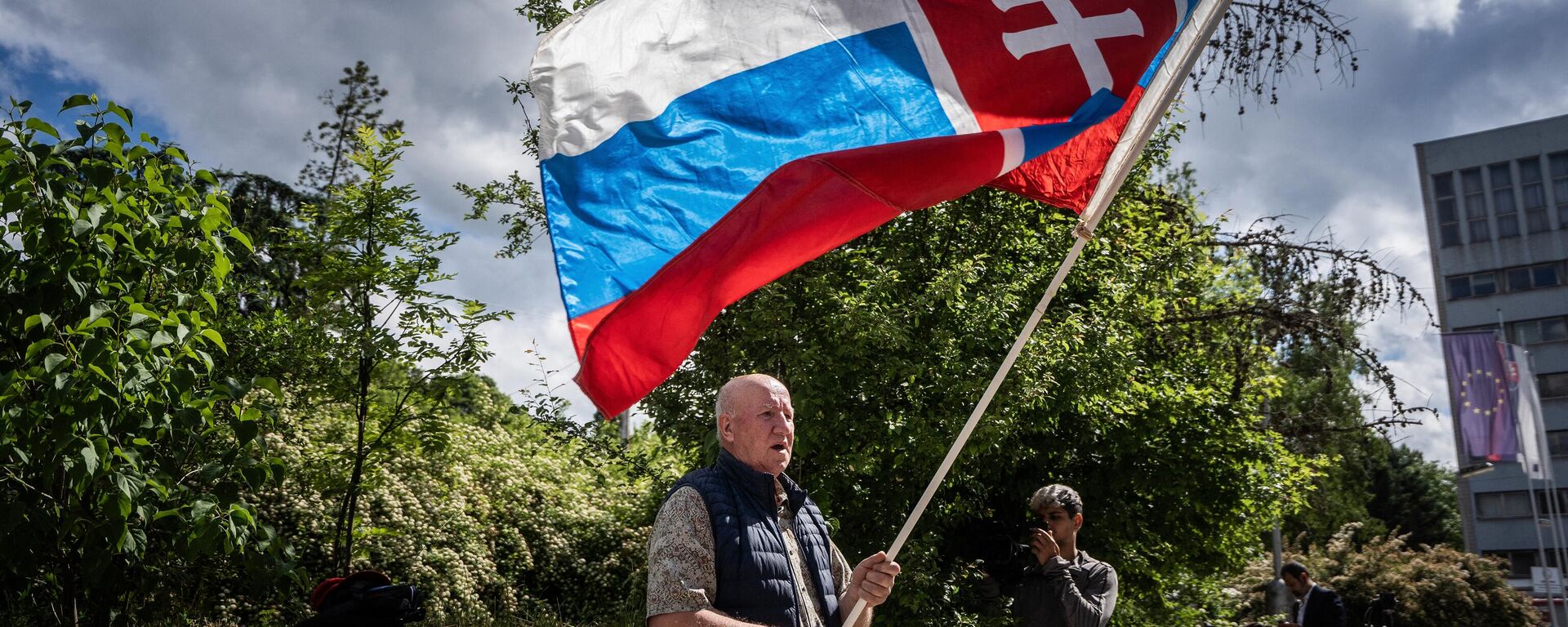 Picture taken on May 16, 2024 shows a man named Vladimir Petko holding a Slovakia flag, who came to pray in front of the hospital in Banska Bystrica, Slovakia where Slovak Prime Minister Robert Fico is being treated after he was shot multiple times the day before. Slovak Prime Minister Robert Fico's condition has stabilized overnight but is still very serious, the deputy prime minister said on May 16, 2024. - Sputnik International, 1920, 16.05.2024