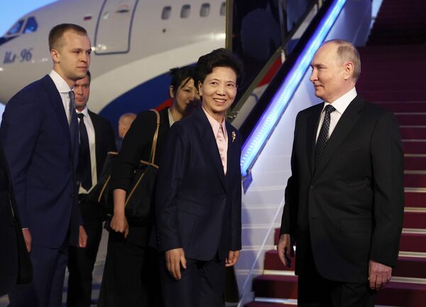Russian President Vladimir Putin shakes hands with Chinese State Councilor Shen Yiqin upon arriving at the Beijing Capital International Airport, in Beijing, China - Sputnik International
