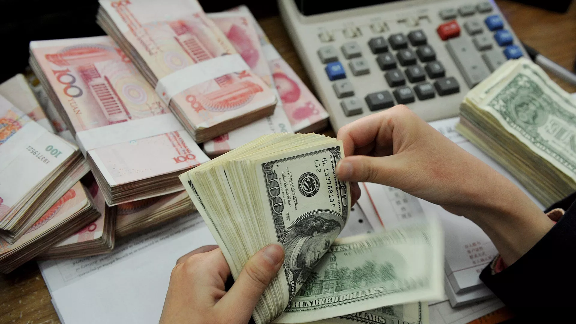 This photo taken n January 16, 2011 shows a bank teller counting stacks of US dollars and Chinese 100-yuan notes at a bank in Hefei, east China's Anhui province. - Sputnik International, 1920, 18.05.2024