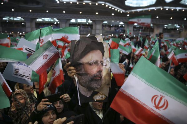 Raisi's supporters hold his photo and wave the Iraninan flag during a 2017 presidential election rally in Tehran - Sputnik International