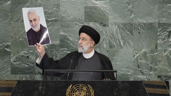 President of Iran Ebrahim Raisi holds up a photo of slain Iranian Gen. Qassem Soleimani, as he addresses the 77th session of the United Nations General Assembly - Sputnik International