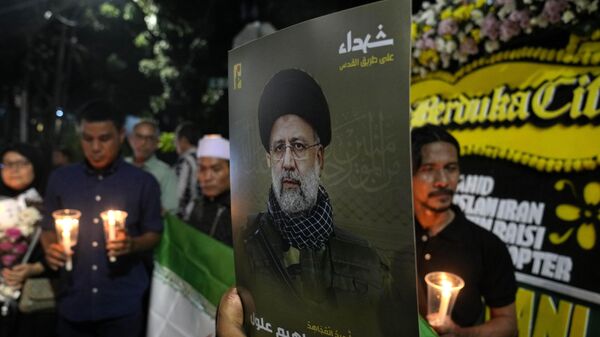 A man holds a portrait of Iranian President Ebrahim Raisi during a candlelight vigil outside the Embassy of Iran in Jakarta, Indonesia, Monday, May 20, 2024 - Sputnik International