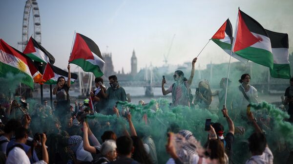 Протестующие машут палестинскими флагами во время пропалестинской демонстрации на мосту Ватерлоо в Лондоне - Sputnik International