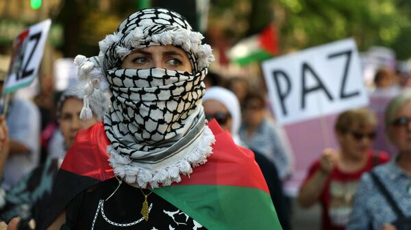 A woman wrapped in a Palestinian flag and wearing a keffiyeh takes part in a demonstration in support of the Palestinian people from the Gaza Strip, in Madrid on May 11, 2024.  - Sputnik International