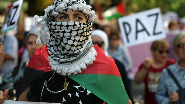 A woman wrapped in a Palestinian flag and wearing a keffiyeh takes part in a demonstration in support of the Palestinian people from the Gaza Strip, in Madrid on May 11, 2024.  - Sputnik International