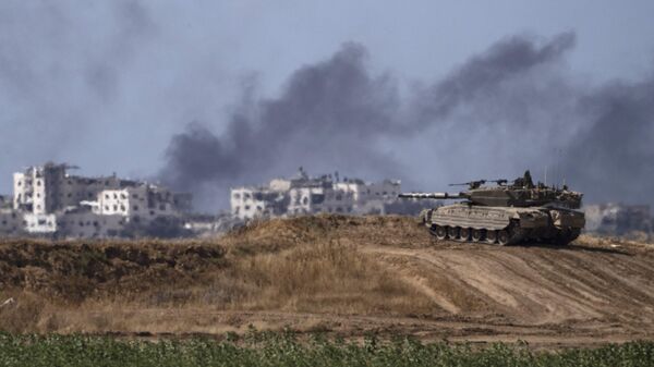 Backdropped by smoke rising to the sky after an explosion in the Gaza Strip, an Israeli tank stands near the Israel-Gaza border as seen from southern Israel, Monday, May 13, 2024 - Sputnik International