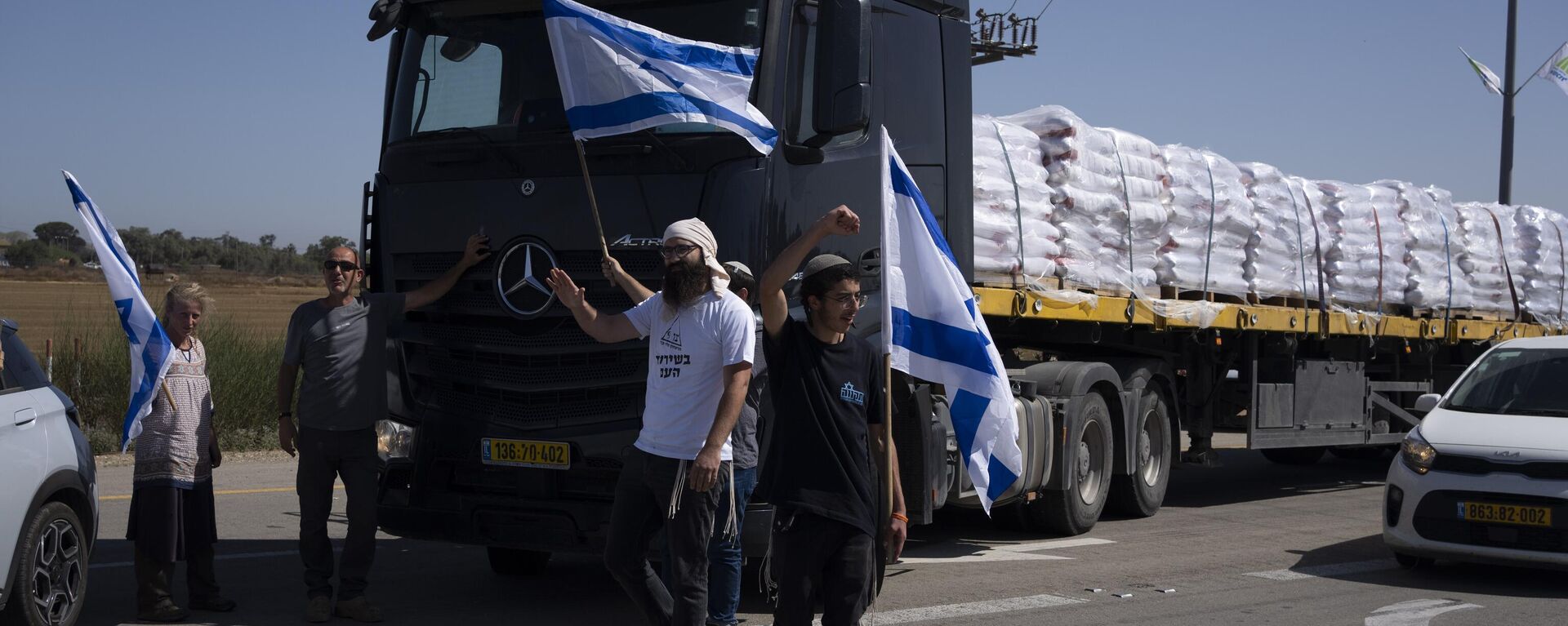 Holding Israeli flags people stand in front of trucks carrying humanitarian aid as they try to stop them from entering the Gaza Strip in an area near the Kerem Shalom border crossing in southern Israel, Thursday, May 9, 2024. (AP Photo/Leo Correa) - Sputnik International, 1920, 27.05.2024