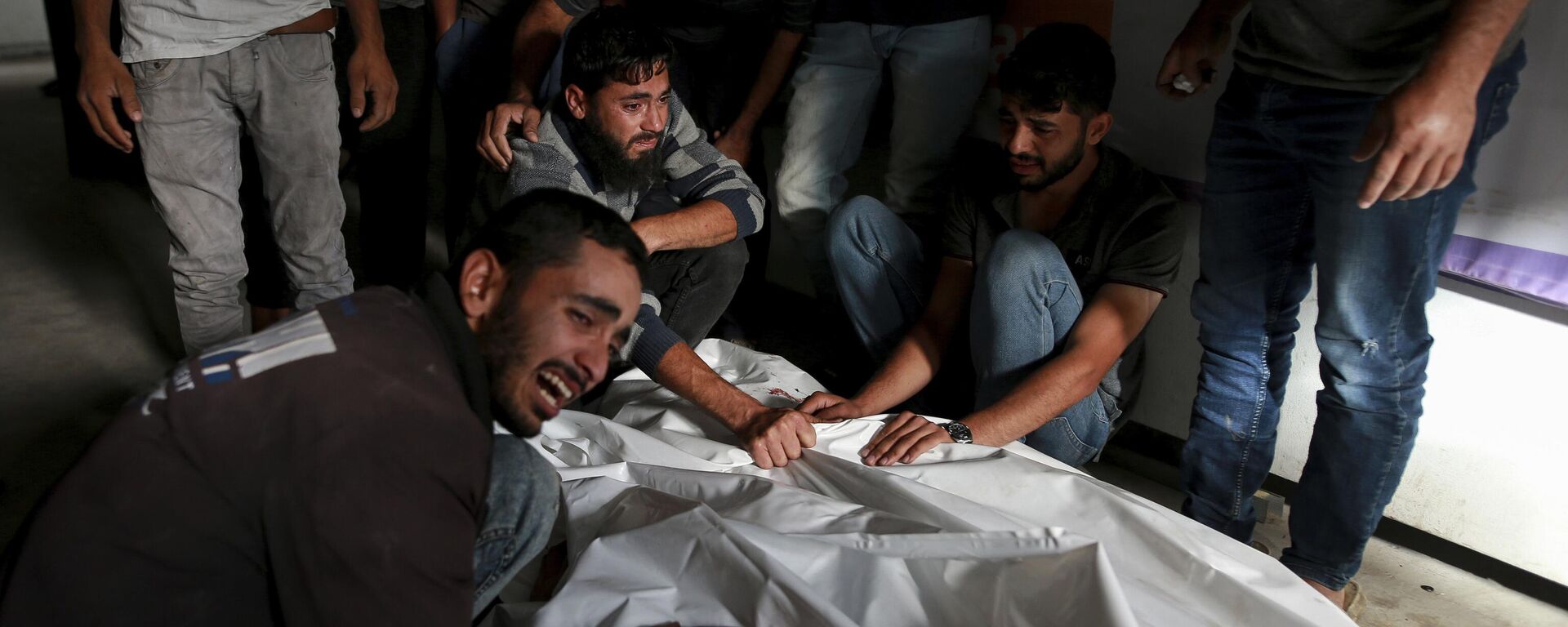 Palestinians mourn over the bodies of relatives killed in an Israeli airstrike, at a morgue in Rafah, Gaza Strip, Monday, May 27, 2024. Palestinian health workers said Israeli airstrikes Sunday killed at least 35 people sheltering in a tent camp for displaced people. Israel's army confirmed the strike and said it hit a Hamas installation and killed two senior Hamas militants. (AP Photo/Jehad Alshrafi) - Sputnik International, 1920, 29.05.2024