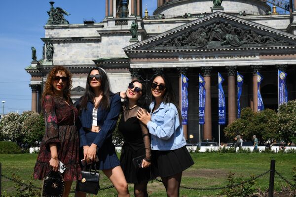 Women posing for a photo in front of the Saint Isaac&#x27;s Cathedral that has been decorated with SPIEF-themed banners. - Sputnik International