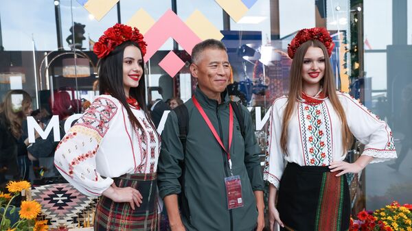 An international guest taking a photo with the forum's members dressed in traditional female costumes of the Donetsk People's Republic (DPR) - Sputnik International