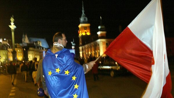 A man covered with the EU flag and waving the Polish national flag walks down the street of the Old Town in Warsaw. File photo - Sputnik International