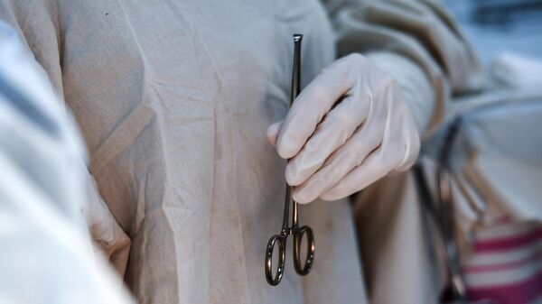 An assistant holds a surgical clamp during an operation - Sputnik International