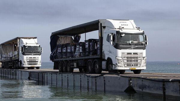 Trucks loaded with humanitarian aid from the United Arab Emirates and the United States Agency for International Development cross the Trident Pier before arriving on the beach on the Gaza Strip, May 17, 2024.  - Sputnik International