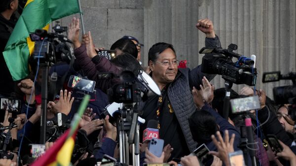 Bolivian President Luis Arce raises a clenched fist surrounded by supporters and media, outside the government palace in La Paz, Bolivia, Wednesday, June 26, 2024 - Sputnik International