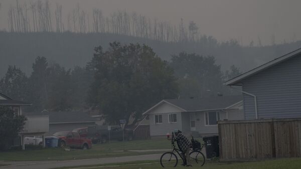 A person rides a bicycle on a smoky day due to wildfires in Fort McMurray, Canada, Sep. 2, 2023 - Sputnik International