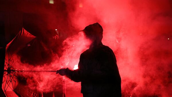 A demonstrator holds an umbrella in a cloud of smoke during a gathering for the election night following the second round results of France's legislative election at Republique Square in Paris on the night of July 8, 2024. - Sputnik International