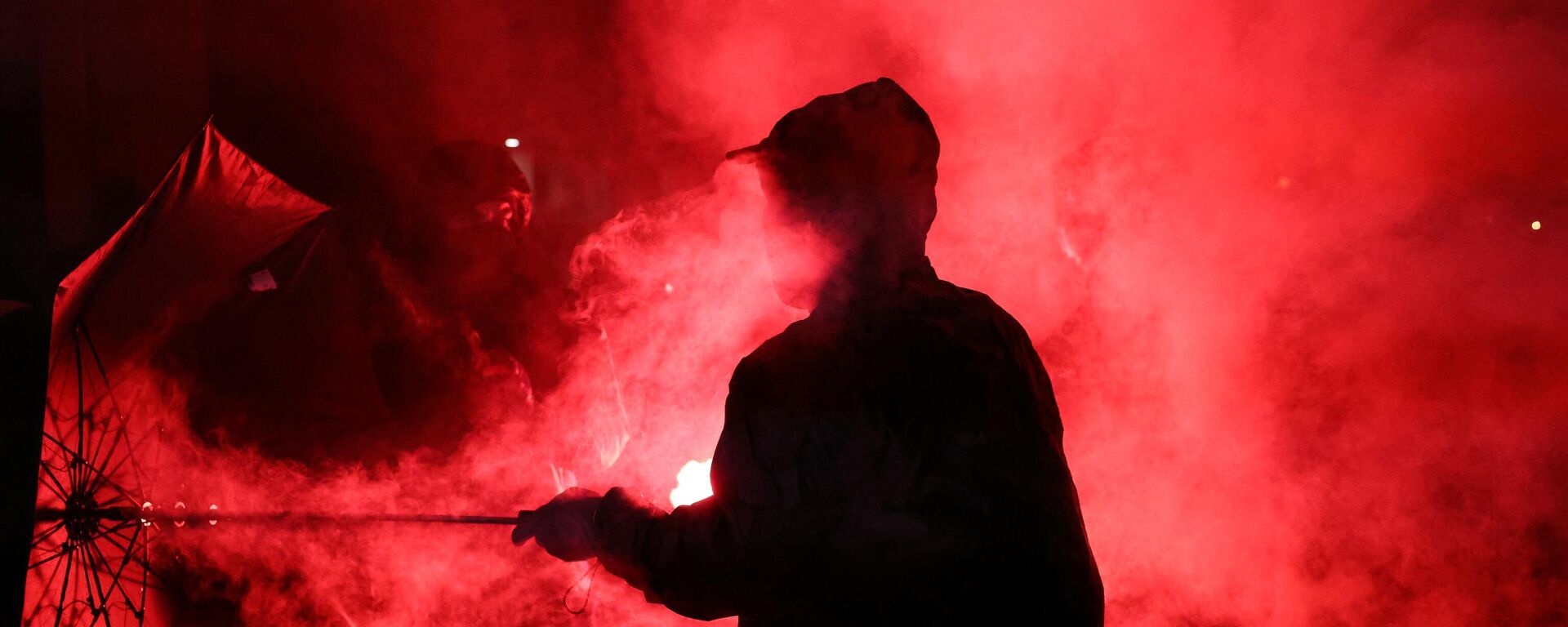 A demonstrator holds an umbrella in a cloud of smoke during a gathering for the election night following the second round results of France's legislative election at Republique Square in Paris on the night of July 8, 2024. - Sputnik International, 1920, 08.07.2024