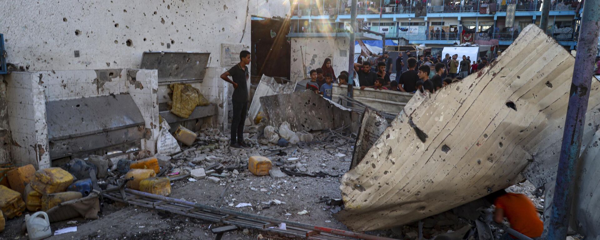 Palestinians look at the aftermath of the Israeli airstrike on a U.N.-run school–turned-shelter that killed at least 16 in the Nusseirat refugee camp in the Gaza Strip, Saturday, July 6, 2024, according to Gaza’s Health Ministry. - Sputnik International, 1920, 09.07.2024