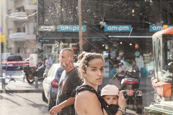 A woman carrying a baby walks past shattered glass in the aftermath of the explosion. - Sputnik International