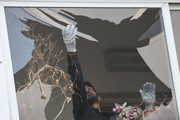 An Israeli policeman collects glass shrapnel from the window of a building that was damaged by the explosion. - Sputnik International