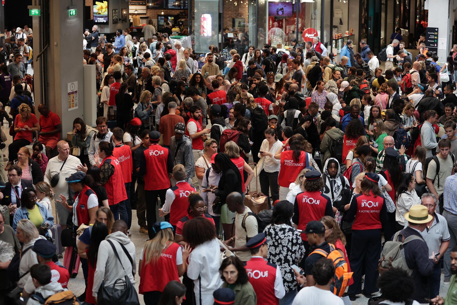 Employees of SNCF railway company speak to passengers waiting for their trains' departure at the Gare Montparnasse train station in Paris on July 26, 2024 as France's high-speed rail network was hit by malicious acts disrupting the transport system hours before the opening ceremony of the Paris 2024 Olympic Games. According to SNCF a massive attack on a large scale hit the TGV network and many routes will have to be cancelled. SNCF urged passengers to postpone their trips and stay away from train stations. - Sputnik International, 1920, 26.07.2024