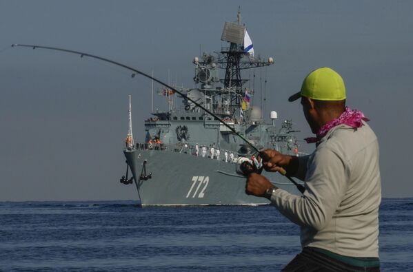 A fisherman winds his fishing rod in front of the frigate Neustrashimy.  - Sputnik International