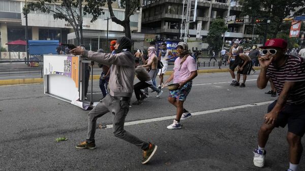 A protester aims a weapon during clashes with police amid demonstrations against the official election results declaring President Nicolas Maduro's reelection in Caracas, Venezuela, Monday, July 29, 2024, the day after the vote. (AP Photo/Fernando Vergara) - Sputnik International