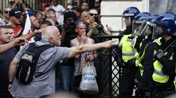 Protestors remonstrate with Police officers during the 'Enough is Enough' demonstration on Whitehall, outside the entrance to 10 Downing Street in central London on July 31, 2024. - Sputnik International