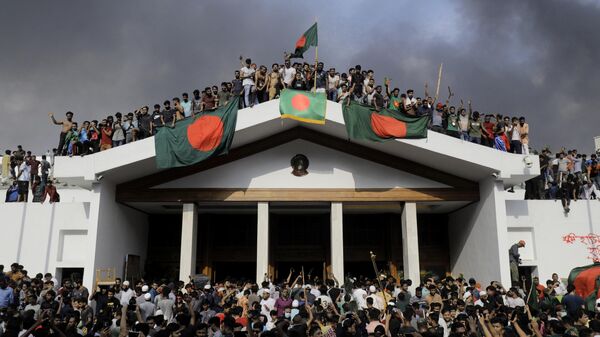 Anti-government protestors display Bangladesh's national flag as they storm Prime Minister Sheikh Hasina's palace in Dhaka on August 5, 2024.  - Sputnik International