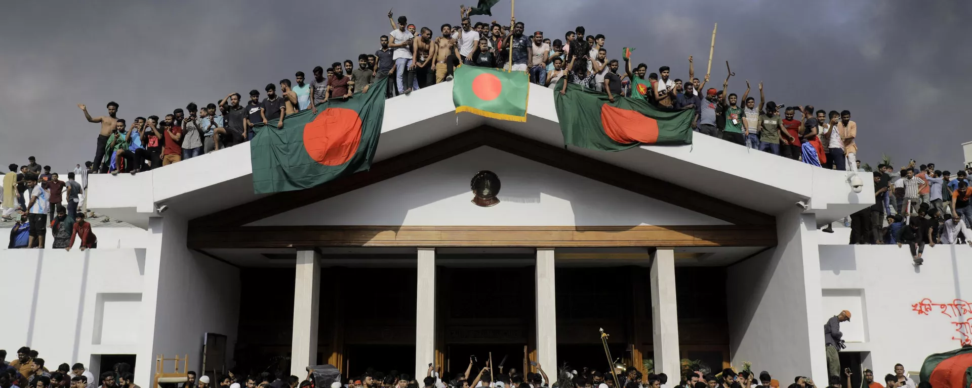 Anti-government protestors display Bangladesh's national flag as they storm Prime Minister Sheikh Hasina's palace in Dhaka on August 5, 2024.  - Sputnik International, 1920, 05.08.2024