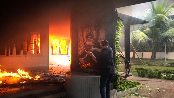 An anti-government protestor vandalises a portrait of Bangladesh's founding father Sheikh Mujibur Rahman as others set the Bangabandhu Memorial Museum on fire in Dhaka on August 5, 2024. - Sputnik International