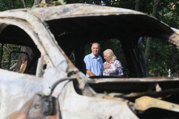 An elderly couple reacts as they see a burnt car. - Sputnik International