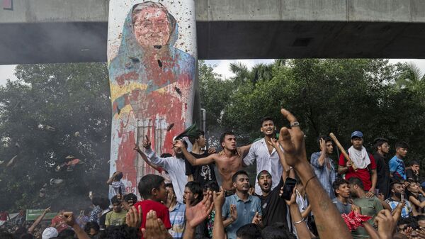 Protesters celebrate beside a defaced portrait of Prime Minister Sheikh Hasina after news of her resignation, in Dhaka, Bangladesh, Monday, Aug. 5, 2024. - Sputnik International