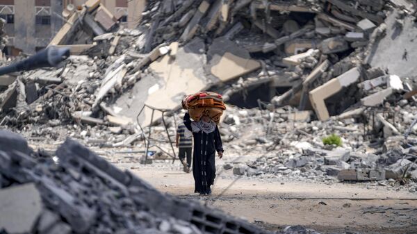 A Palestinian displaced woman by the Israeli air and ground offensive on the Gaza Strip flees from Hamad City. (Aug. 11, 2024.) - Sputnik International