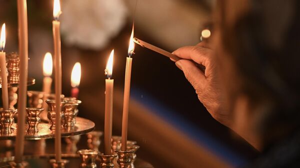 An Orthodox believer lights a candle during a service at the Cathedral of the Nativity in Berdyansk, Zaporozhye region, Russia. - Sputnik International