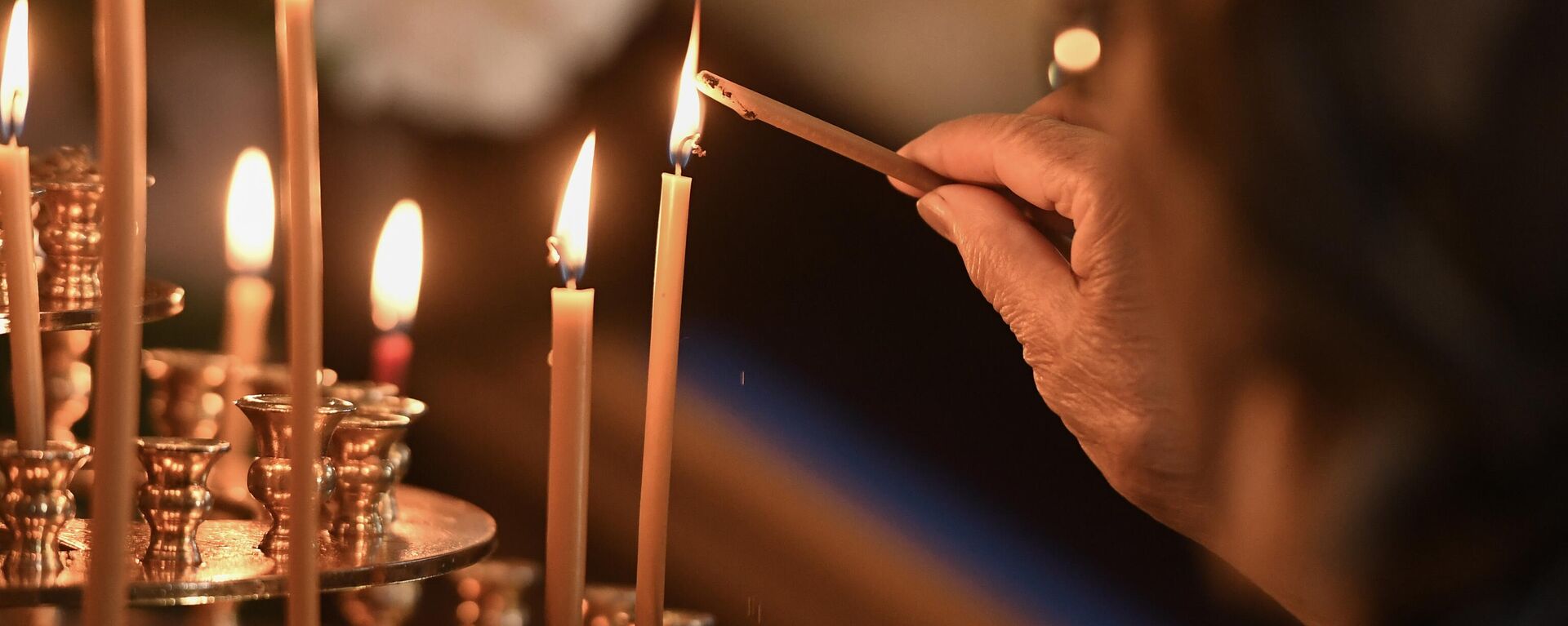 An Orthodox believer lights a candle during a service at the Cathedral of the Nativity in Berdyansk, Zaporozhye region, Russia. - Sputnik International, 1920, 13.08.2024