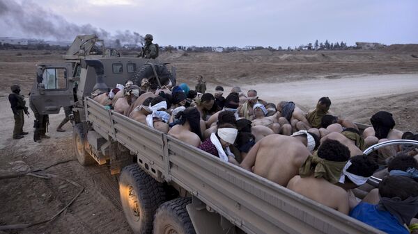 Israeli soldiers stand by a truck packed with bound and blindfolded Palestinian detainees, in Gaza, Friday, Dec. 8, 2023 - Sputnik International