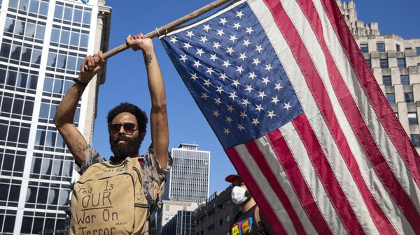 A protester holds a flag at Monument Circle following a non-violent sit-in at the Statehouse in Indianapolis, Saturday, June 6, 2020, against police brutality sparked by the death of George Floyd, who died after being restrained by Minneapolis police officers on May 25 - Sputnik International