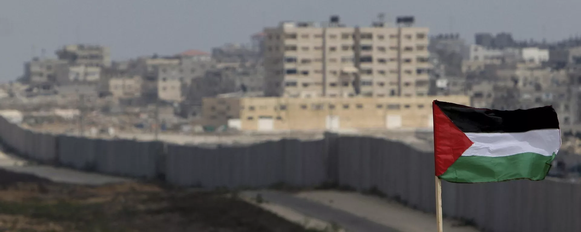 FILE - A Palestinian flag is seen with the background of a section of the wall in the Philadelphi corridor between Egypt and Gaza, on the background, near the southern Gaza Strip town of Rafah. - Sputnik International, 1920, 13.10.2024