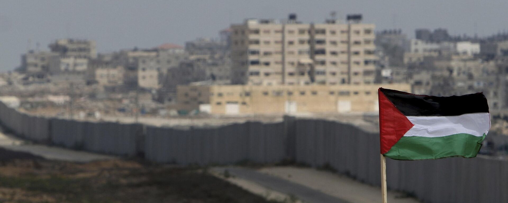 FILE - A Palestinian flag is seen with the background of a section of the wall in the Philadelphi corridor between Egypt and Gaza, on the background, near the southern Gaza Strip town of Rafah. - Sputnik International, 1920, 01.09.2024