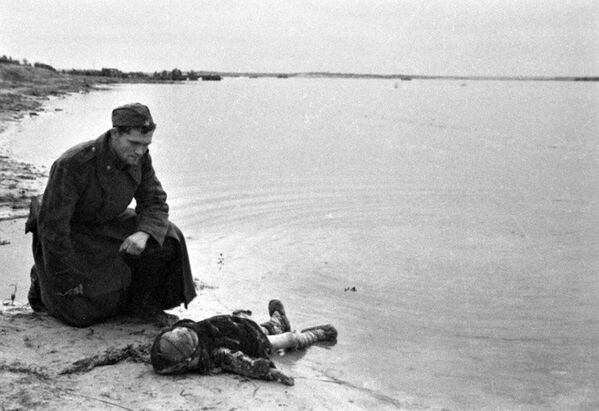 A Soviet soldier on the bank of the Dnepr River mourns a murdered child. - Sputnik International