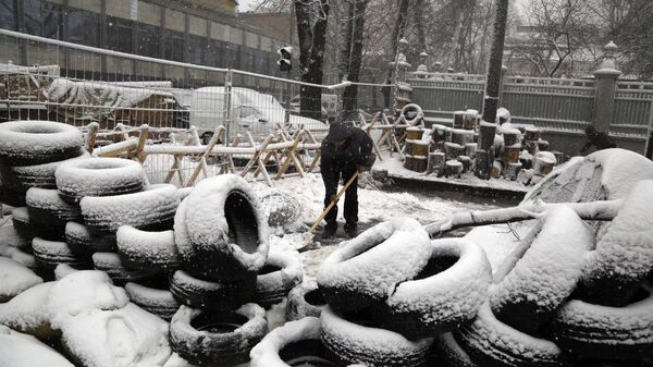 Under heavy snowfall an activist cleans away snow near a tire barricade erected by supporters of the Movement of New Forces, the political party led by Mikheil Saakashvili in front of the parliament building in Kiev, Ukraine, Monday, Dec.18, 2017 - Sputnik International