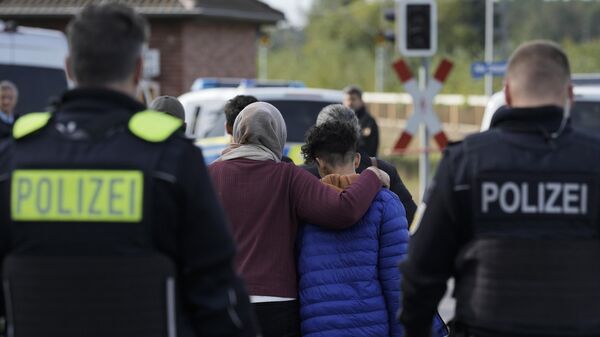 A mother embraces her son after they illegally crossed the border from Poland into Germany and tracked down by a Federal Police patrol in a forest near Forst southeast of Berlin, Germany, Wednesday, Oct. 11, 2023 - Sputnik International