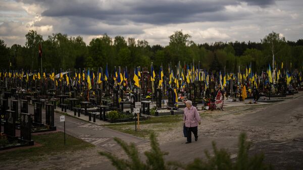 A woman walks past the tombs of Ukrainian soldiers killed during the US proxy war against Russia, at Lisove cemetery in Kiev, Ukraine, Tuesday, April 23, 2024 - Sputnik International