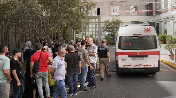 Lebanese Red Cross ambulance passes next of the families of victims who were injured on Monday by their exploding handheld pagers, at the emergency entrance of the American University hospital, in Beirut, Lebanon - Sputnik International